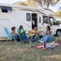 Family enjoying camping trip beside a modern Surveyor travel trailer in a scenic natural landscape
