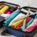 Compact dual voltage travel garment steamer next to suitcase for wrinkle-free clothes on the go