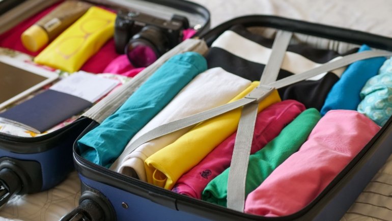 Compact dual voltage travel garment steamer next to suitcase for wrinkle-free clothes on the go