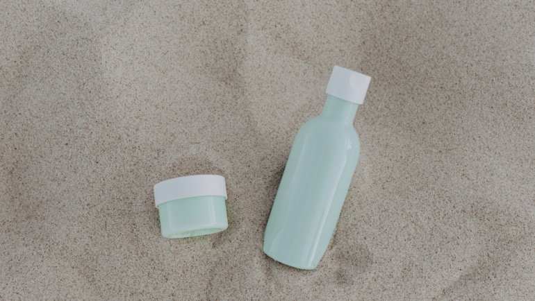 Kevin Murphy Angel Wash travel size shampoo bottle in toiletry bag with beach background for hair care on the go