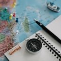 Traveler planning Peru trip with a travel guidebook, maps, and notes on a wooden table