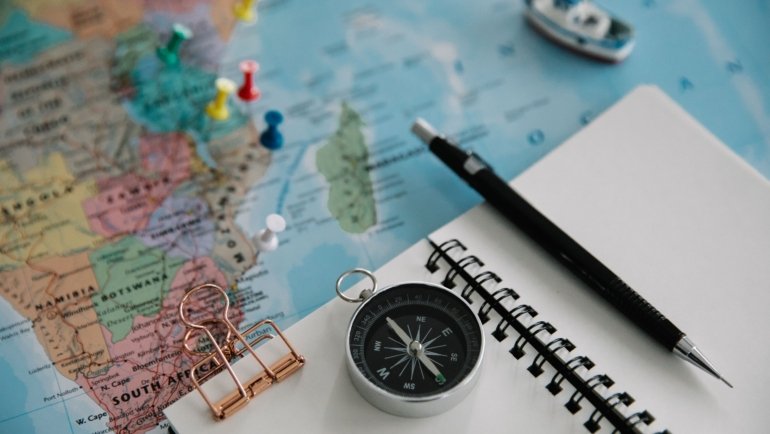 Traveler planning Peru trip with a travel guidebook, maps, and notes on a wooden table