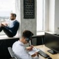 Travel agent helping client plan a customized trip using a laptop in a modern office