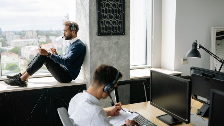 Travel agent helping client plan a customized trip using a laptop in a modern office