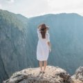 Woman wearing a versatile wool travel dress layered with a scarf, enjoying a scenic outdoor travel destination