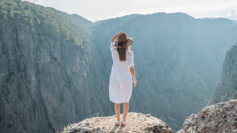 Woman wearing a versatile wool travel dress layered with a scarf, enjoying a scenic outdoor travel destination