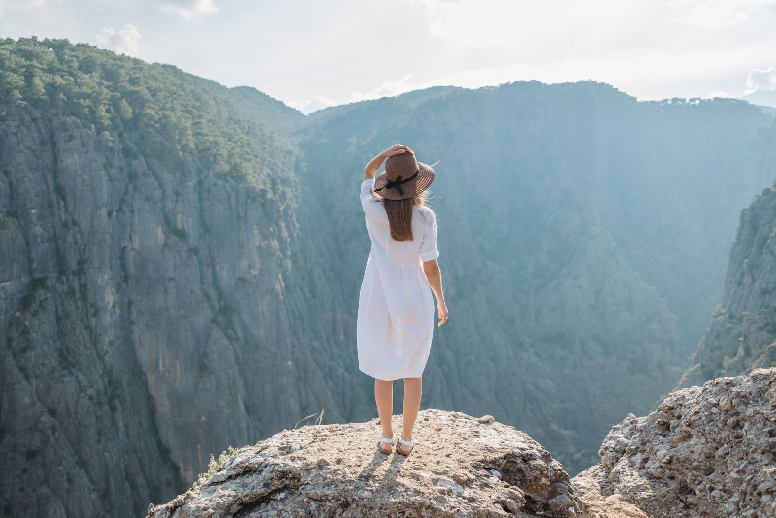 Woman wearing a versatile wool travel dress layered with a scarf, enjoying a scenic outdoor travel destination