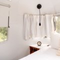 Interior of a rear living room travel trailer with panoramic windows and comfortable seating area overlooking nature