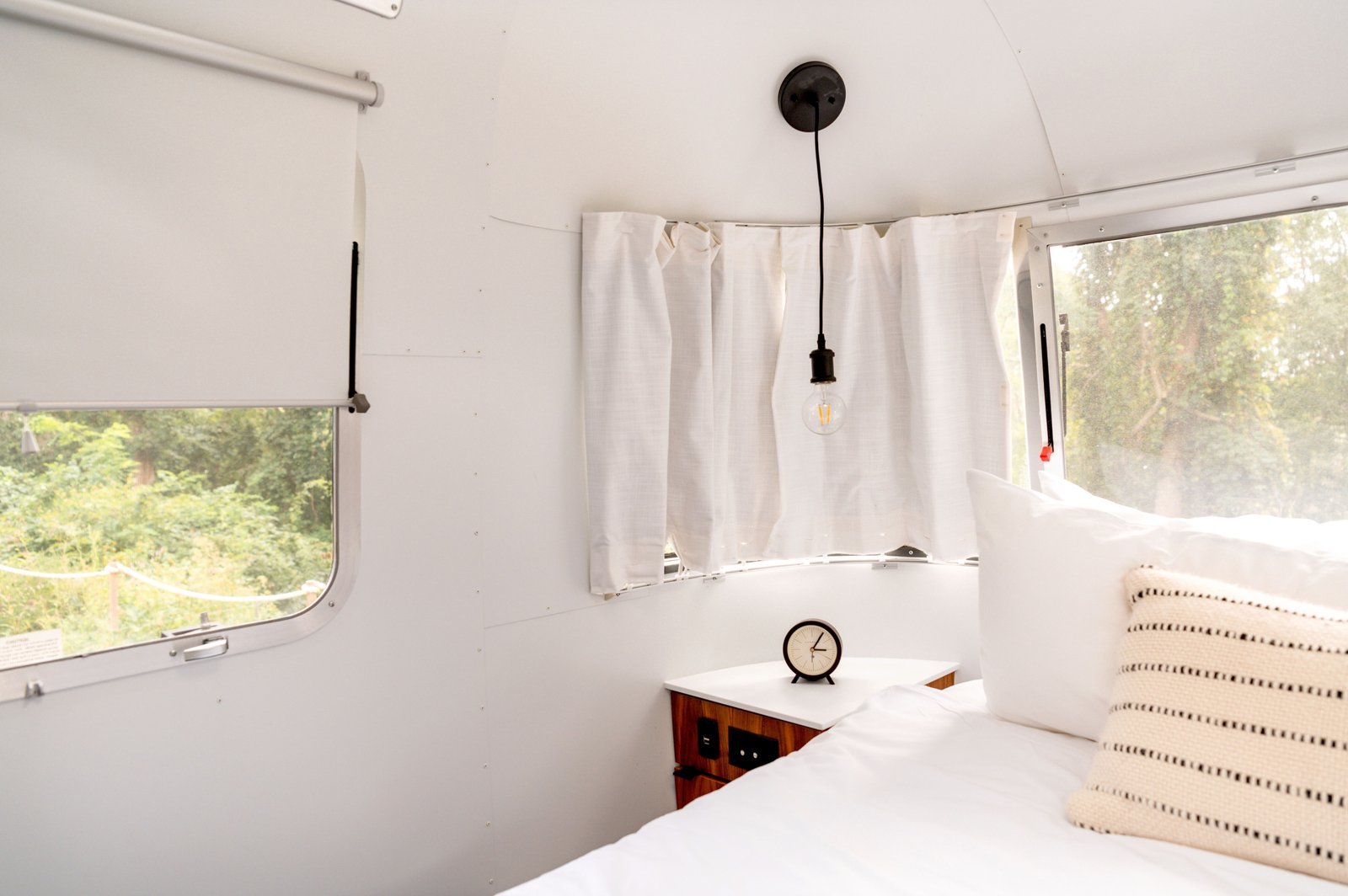 Interior of a rear living room travel trailer with panoramic windows and comfortable seating area overlooking nature