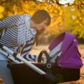 Modern parent using Britax Smile 3 travel system stroller with baby outdoors, showcasing safety and comfort