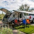 Person leveling a travel trailer with leveling blocks and bubble level on a calm camping site