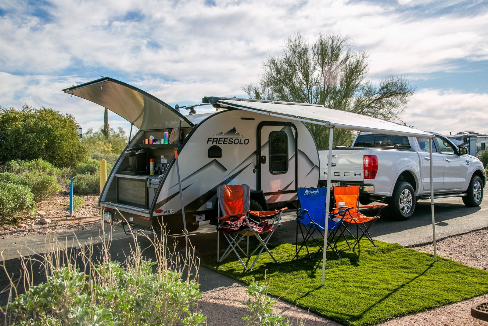 Person leveling a travel trailer with leveling blocks and bubble level on a calm camping site