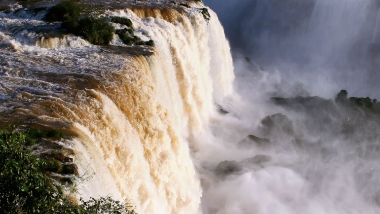 Stunning Iguazu Falls waterfall surrounded by green rainforest under clear sky