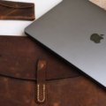 Leather travel pouch with organized travel essentials including passport, tickets, and gadgets on a stylish background