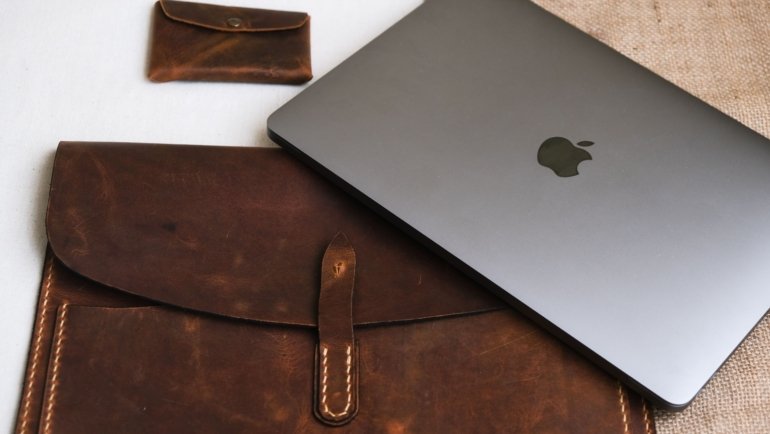 Leather travel pouch with organized travel essentials including passport, tickets, and gadgets on a stylish background