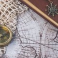 Leather travelers notebook open with pen and travel accessories on wooden table, perfect for journaling and travel planning