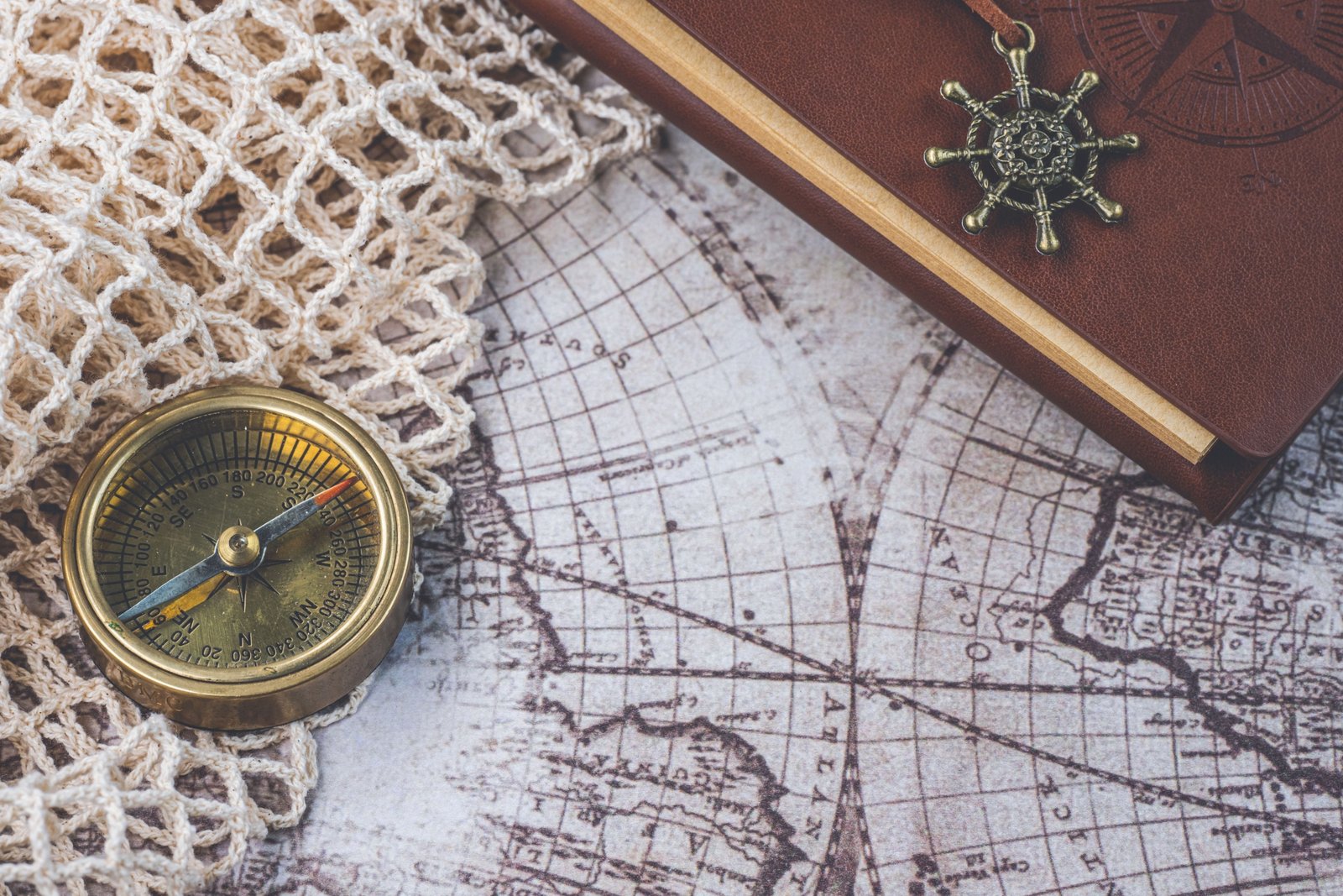 Leather travelers notebook open with pen and travel accessories on wooden table, perfect for journaling and travel planning