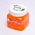Travel size aloe vera gel bottle next to backpack and sunglasses for soothing and moisturizing skin care on the go