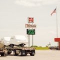 Busy truck stop fuel station with large trucks refueling and convenience store near highway