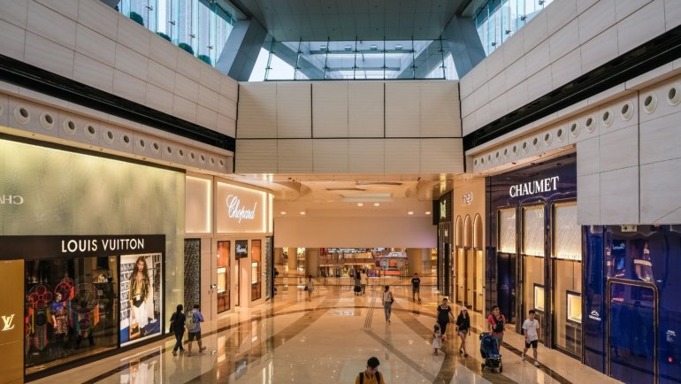 Affluent Asian travelers shopping at a luxury duty-free store with digital displays and exclusive products
