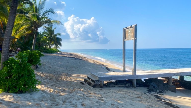 Sunny tropical beach in Honduras with clear skies and turquoise waters during the dry season