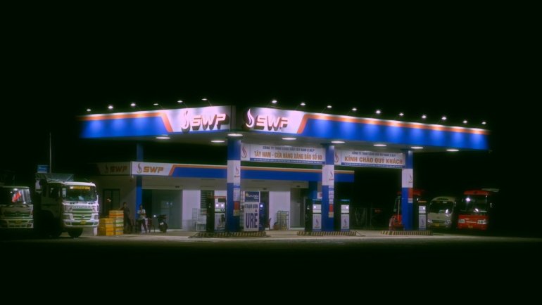 Modern commercial truck stop with trucks parked, fuel pumps, and traveler amenities for long-haul drivers