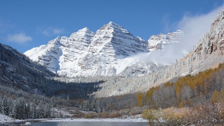 Scenic Aspen mountain landscape with snowy peaks and lush green trails representing winter and summer activities
