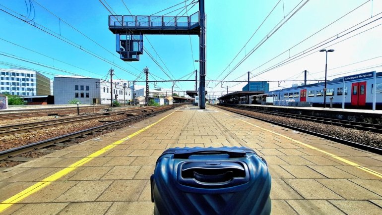 Lightweight rolling luggage and backpacks at a European train station platform with passengers preparing for train travel
