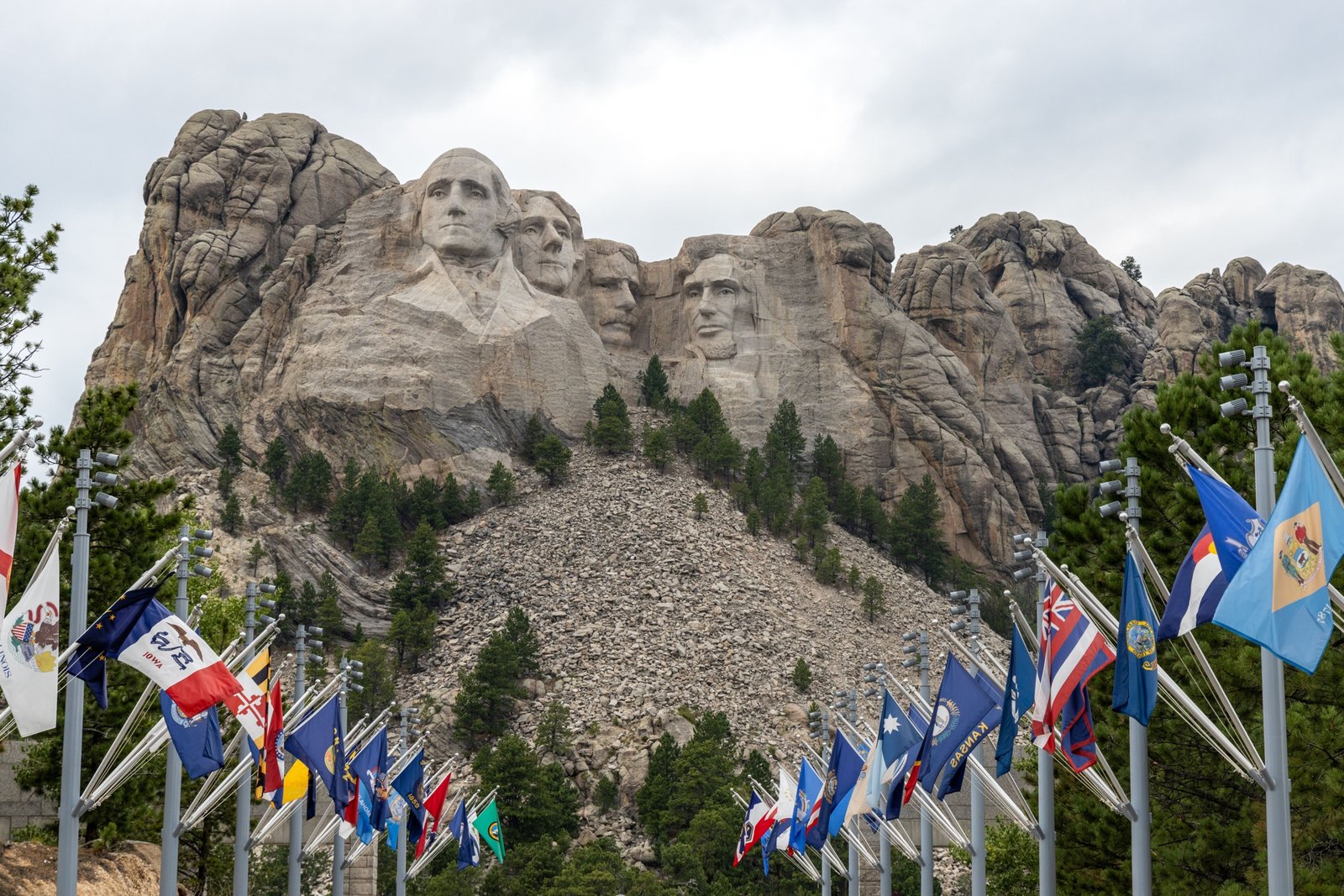 Tourists visiting Mt Rushmore National Memorial during a guided travel package tour with clear blue skies and scenic Black Hills backdrop