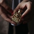 Delina perfume travel size bottle next to a purse, showcasing a luxury fragrance perfect for travel and daily freshness