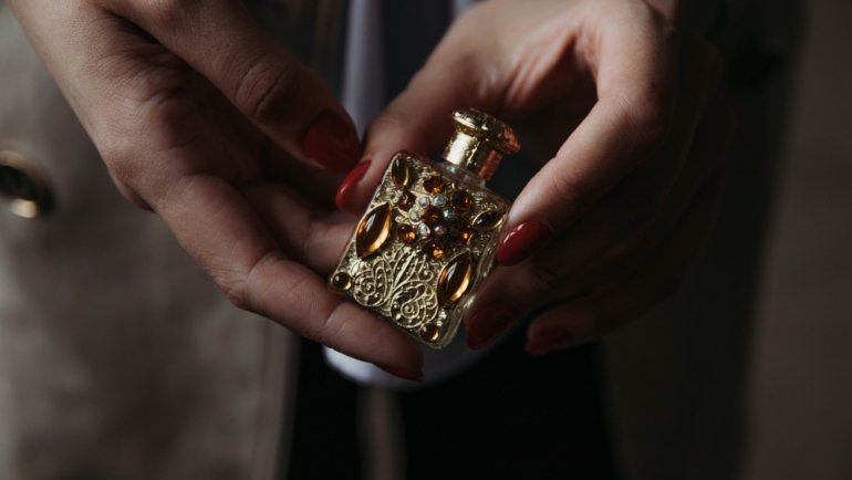 Delina perfume travel size bottle next to a purse, showcasing a luxury fragrance perfect for travel and daily freshness