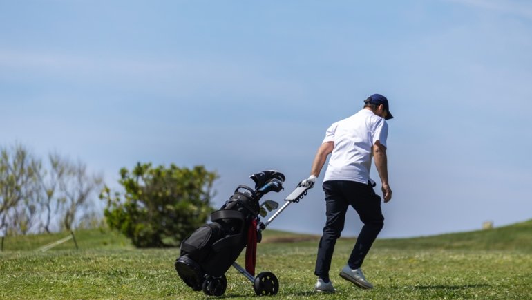 Golfer carrying golf bag at airport representing golf travel insurance and equipment protection