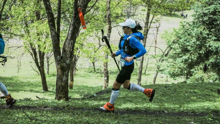 Ultramarathon runner on rugged forest trail during Arkansas Traveller 100 race at sunrise
