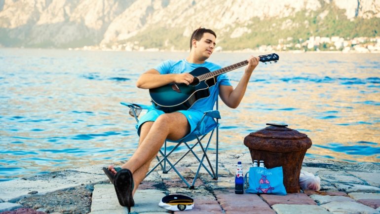 Foldable travel guitar being played outdoors by a traveler, highlighting portability and convenience for musicians on the go