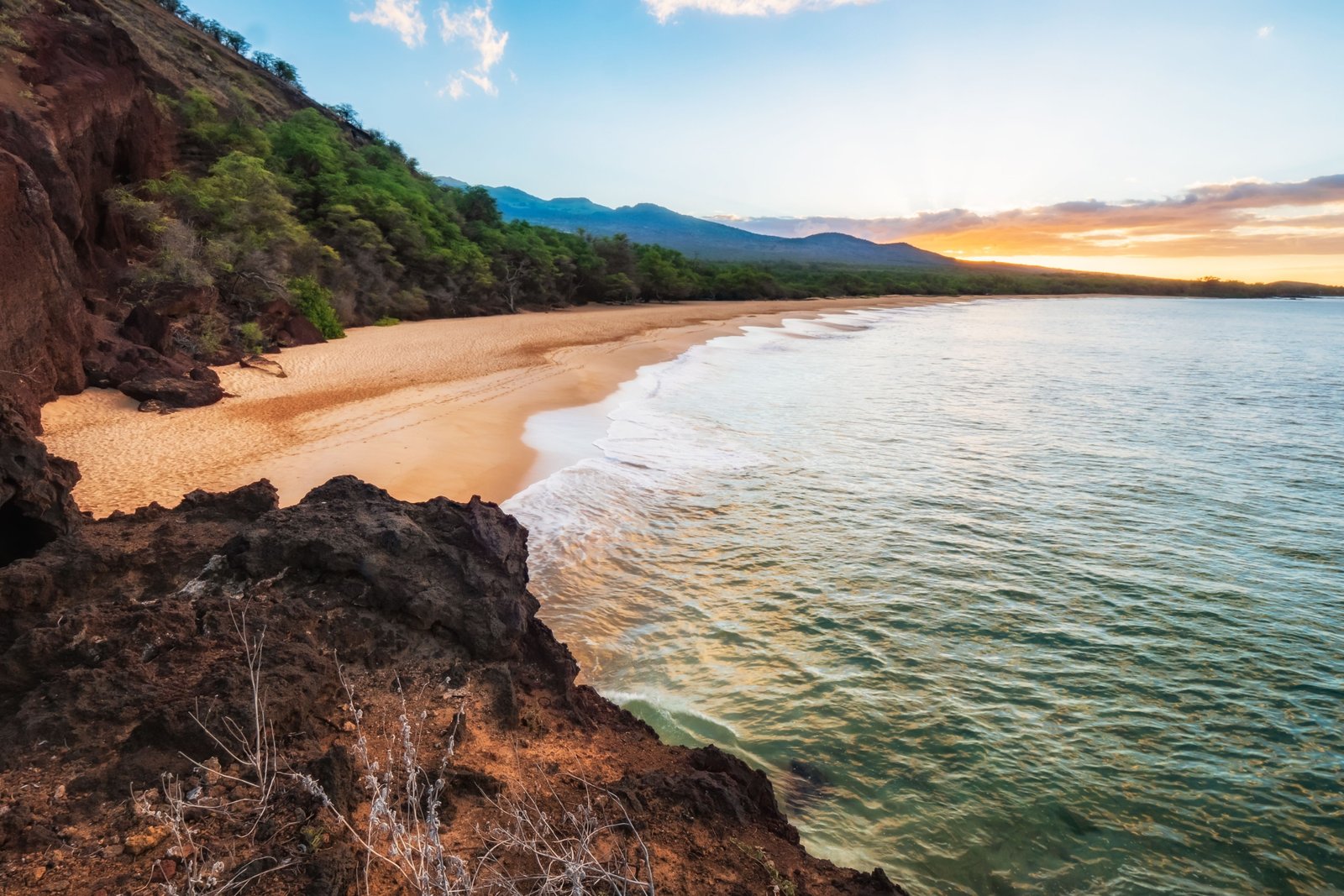 Beautiful Maui tropical beach at sunset with calm ocean waves and lush green landscape