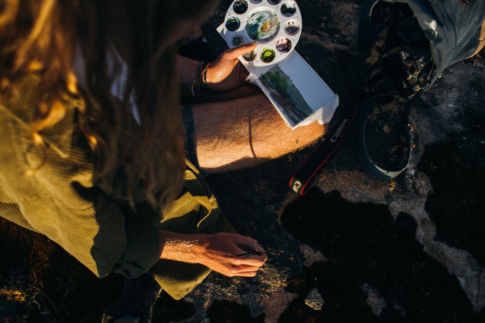 Artist using a compact watercolor travel set to paint outdoors in nature, illustrating portable watercolor painting on the go