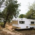 Parked travel trailer secured with stabilizer jacks and wheel chocks during windy weather for safety