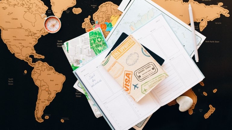 Person planning a trip with an Albania travel guide book and map showing destinations and cultural sites