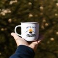 Funny travel mug with humorous quote held by traveler outdoors, showcasing personality and joyful morning routine