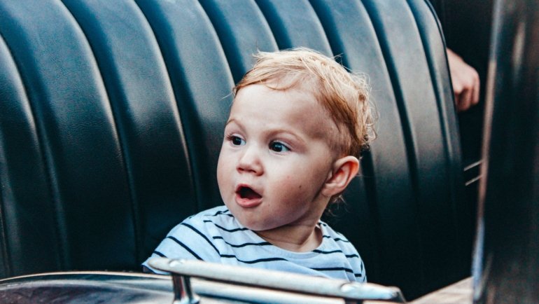Toddler safely and comfortably seated in a travel car seat inside a family car during a road trip