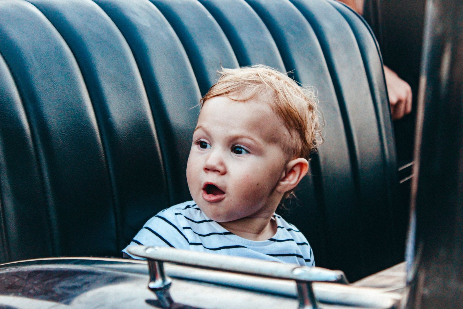 Toddler safely and comfortably seated in a travel car seat inside a family car during a road trip