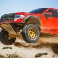 Ford F150 truck with long travel suspension driving on rough off-road terrain