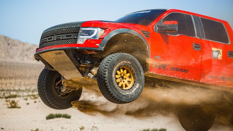 Ford F150 truck with long travel suspension driving on rough off-road terrain