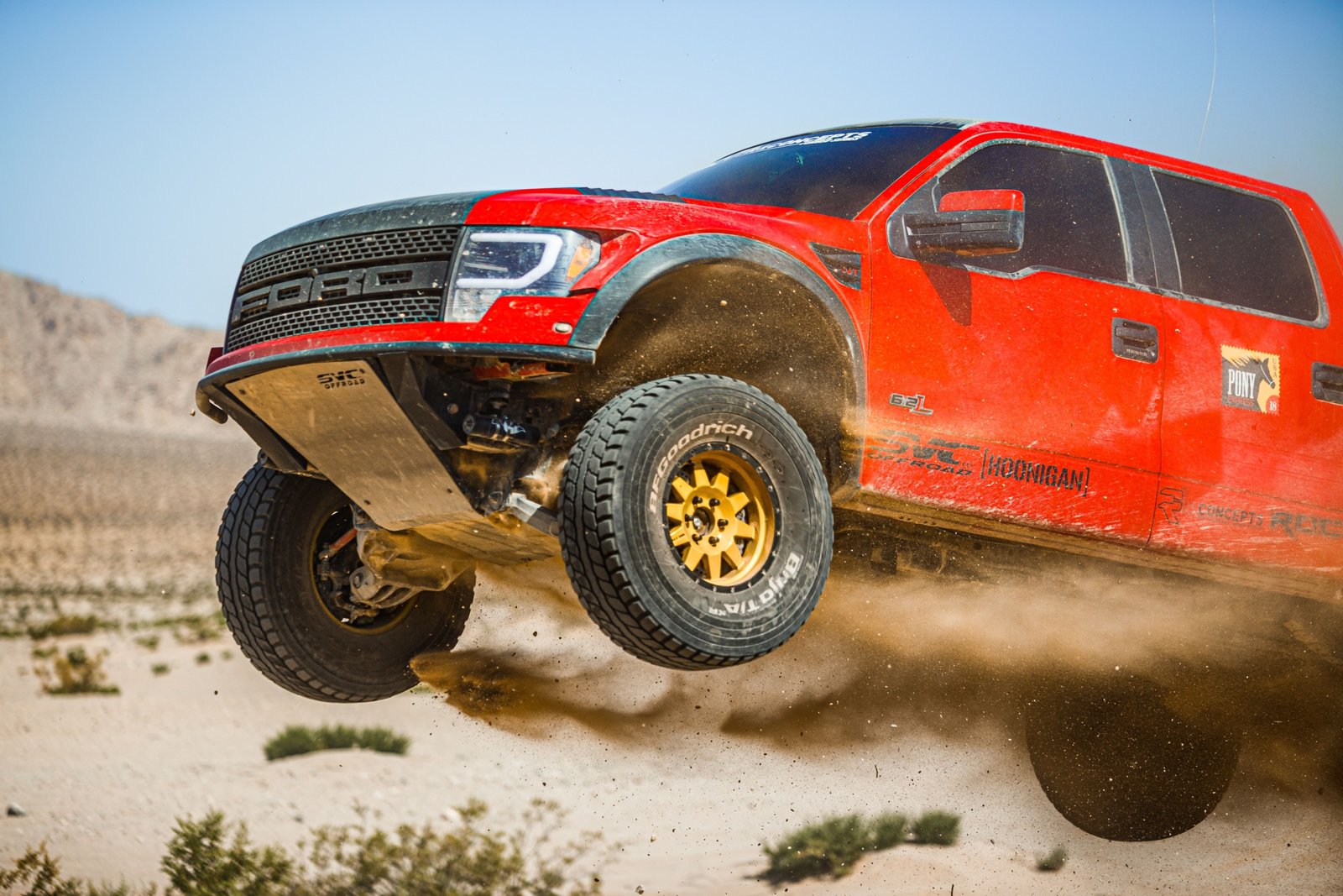 Ford F150 truck with long travel suspension driving on rough off-road terrain