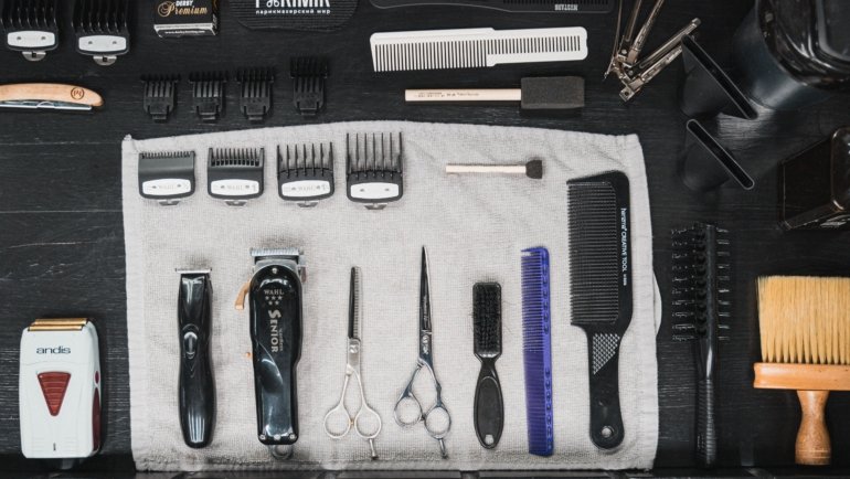 Barber travel bag open with organized grooming tools including scissors, clippers, and combs for professional use