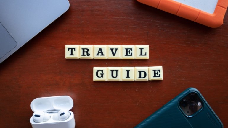 Traveler using AI travel planning tools on laptop and smartphone for personalized itinerary