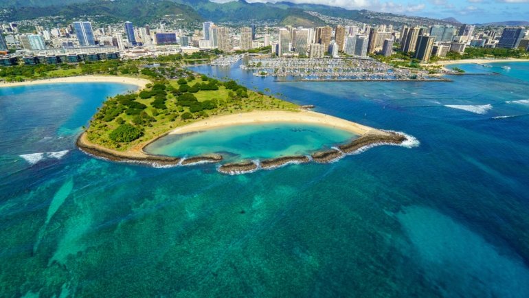 Traveler reading an Oahu travel guide book with scenic Hawaiian landscape in the background