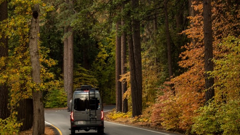 A motorhome driving on a scenic road surrounded by nature, symbolizing freedom and comfortable travel adventures
