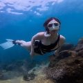 Traveler snorkeling with lightweight travel snorkel fins exploring colorful coral reef