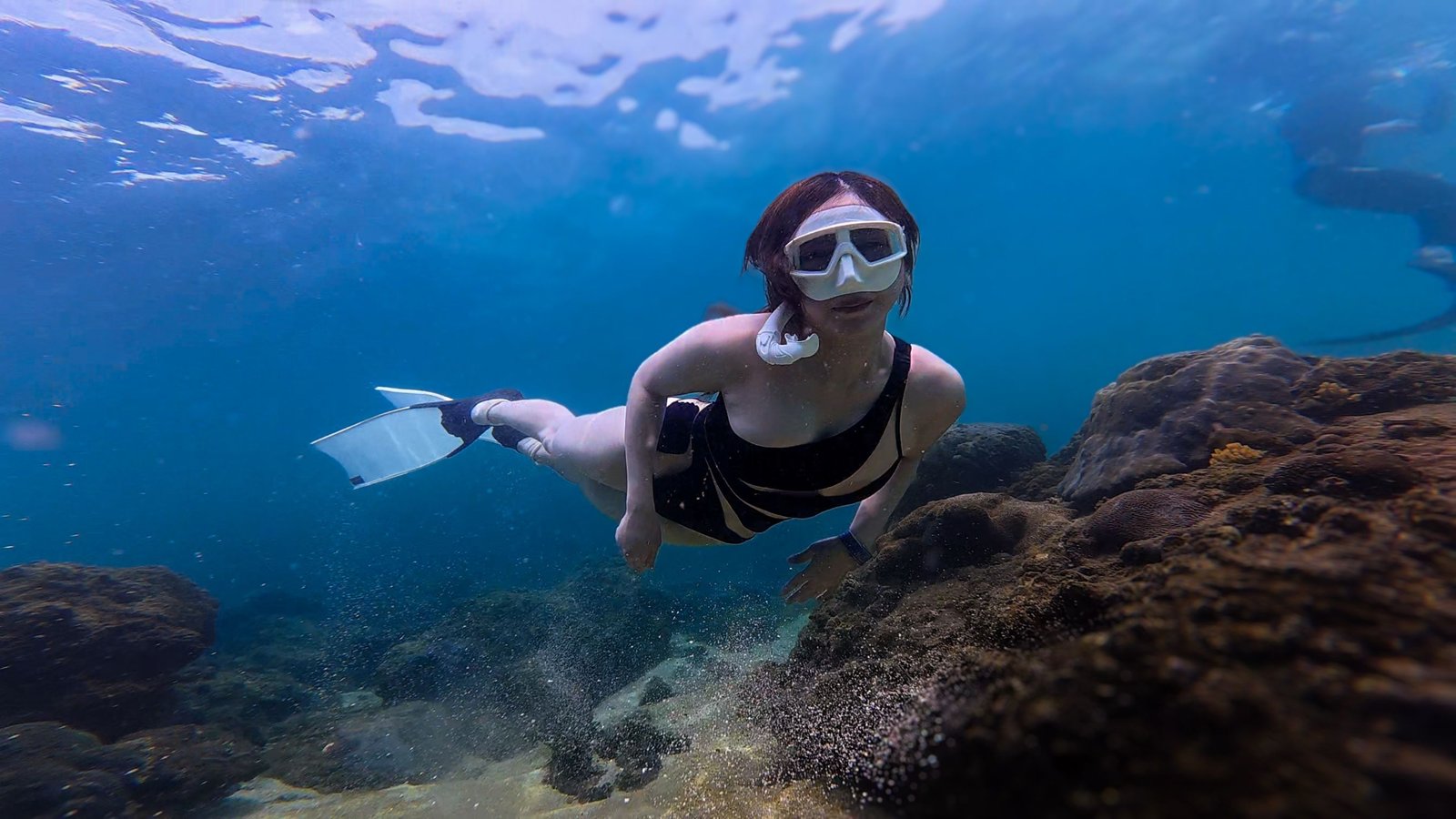 Traveler snorkeling with lightweight travel snorkel fins exploring colorful coral reef